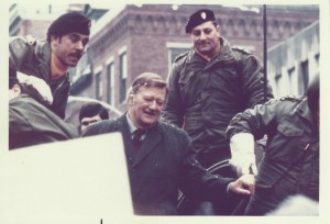 John Wayne, Joe Toplyn, and U.S. Army servicemen ride into Harvard Square on an armored personnel carrier on January 15, 1974.