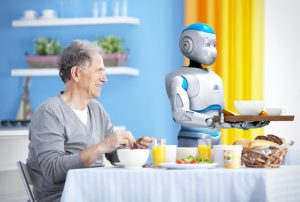 A humanoid robot serves breakfast to a senior citizen.